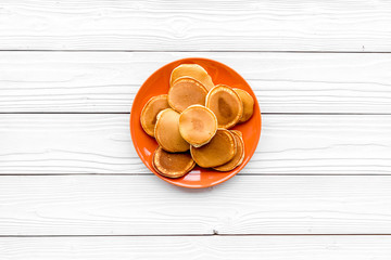 Homemade pancakes on orange plate. White wooden background top view copy space