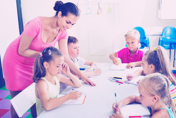 Obraz na płótnie Canvas Kids writing together with tutor at school class