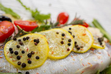 sea bass with vegetables and spices on white wooden background