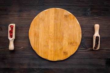 Make menu or write recipe. Mock up for menu or recipe. Wooden cutting board near spices and ingredients on dark wooden background top view
