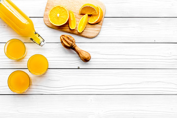 Make orange juice. Juicer, beverage in bottle and glasses near slices of oranges on white wooden...