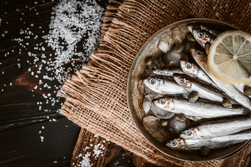 raw fresh fish on a silver platter with ice capers and lemon - obrazy, fototapety, plakaty
