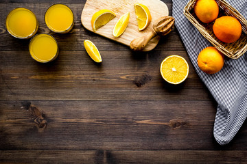 Squeeze juice from oranges. Juicer and slices of oranges on dark wooden background top view copy space