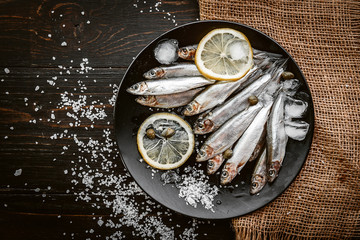 raw fresh fish on a plate with salt and lemon in a rustic style on a wooden surface