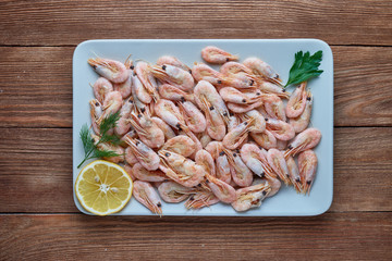 Delicious boiled shrimps with lemon and greens on a plate