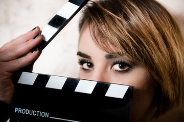 Pretty blonde young woman eyes behind movie clapper board