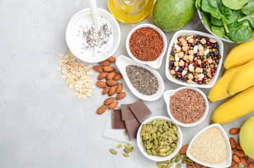 Healthy food nutrition dieting concept. Banana, chocolate, spinach, avocado, apple, quinoa, chia, flax seeds, yogurt, almond, beans, oat, pumpkin seeds, olive oil. Top view, flat lay, copy space. - obrazy, fototapety, plakaty