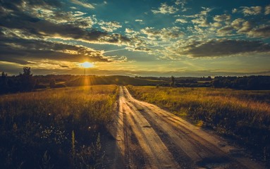 A beautiful shot of a path through a green meadow with a bright sunset sky