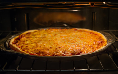 Handmade pizza is cooking in oven. Gold baked cheese as topping 