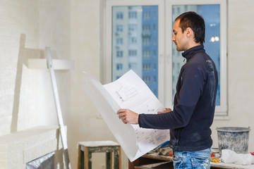 Portrait of an architect builder studying layout plan of the rooms serious civil engineer working
