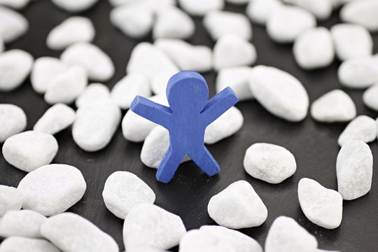 Ein blauer Mann steht alleine in einer Gruppe wei&szlig;er Kieselsteine