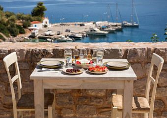 A table served for two with snacks and drinks on the summer terrace of the hotel room by the seascape.