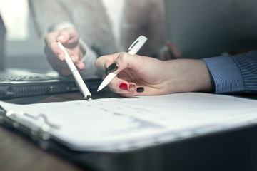 Two businesswoman discuss about grafic with pen in the hands