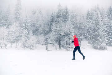 Woman running on snow in winter mountains