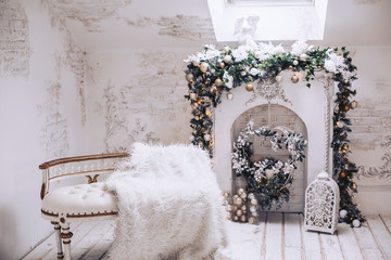White exclusive sofa with gilding on the background of the fireplace. Christmas decorations from Christmas tree branches and toys.
