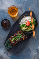 Asian style bbq pork ribs with sauce and rice on wooden board, top view