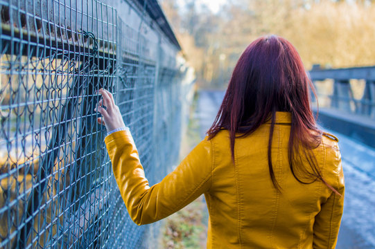 Modelo peliroja de espaldas en el punte con chaqueta amarilla
