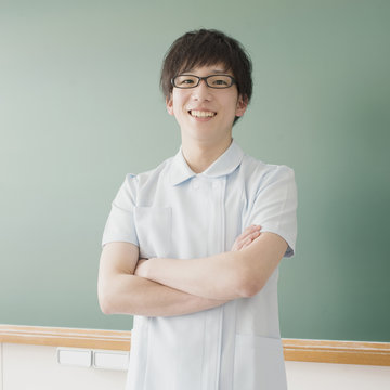 黒板の前で腕組みをする看護学生