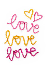The word LOVE is written out with pink and gold tinsel. Love and heart symbols. Flat lay, top view