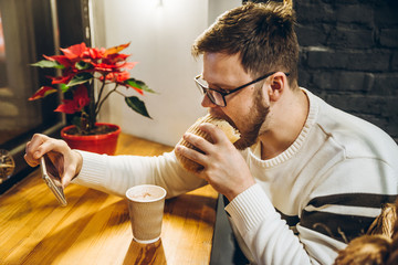 young man eat fast food and watch video on smartphone