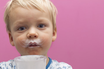 Close-up portrait of cute toddler with sour cream mustache. Copy space