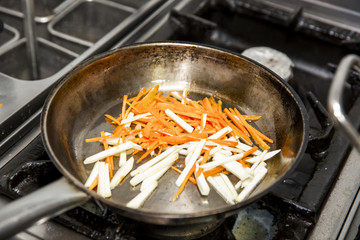 tossing vegetables in a pan