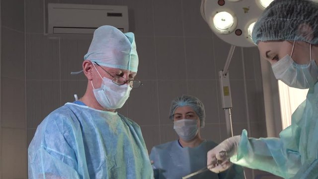 nurse hands over medical instruments during surgery