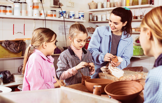 Schoolgirls learning from teacher to make ceramics