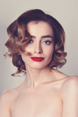 Fototapeta premium Beauty portrait of pretty girl with curly hair, cat eye make-up, red lips. Beauty, cosmetics concept. Healthcare.