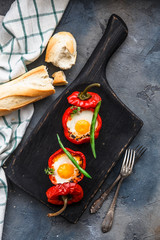 Baked red peppers stuffed with eggs and sausage with bread and green beans, top view