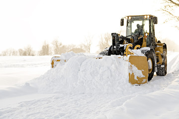 yellow snow plow cleaning a road