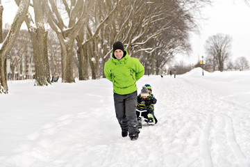 Fototapeta na wymiar Father drag his boy in sled