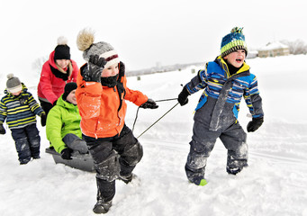 Fototapeta na wymiar Child boy Pulling Sledge Through Snowy Landscape