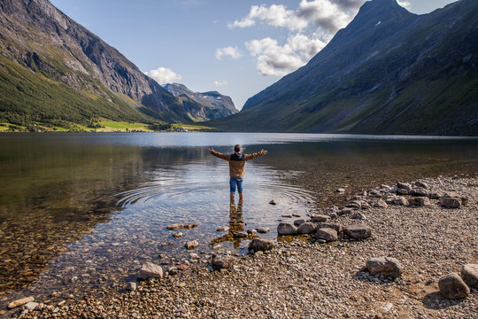 hombre de espaldas con pies en el agua. lago Eidsvatnet, Norway