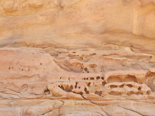 Weathered rose-red sandstone rock face with erosion holes in the ancient Nabataean City of Petra, Jordan
