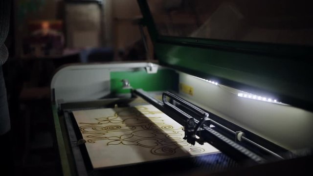 The man opens the lid of the laser systems for cutting plywood with a laser