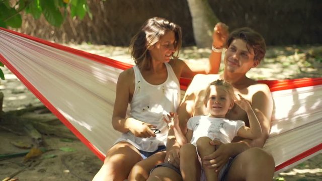 Happy young family with baby in hammock sunny day rapid slow motion 