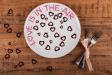 Plate with love message, hearts and pair of forks, red background