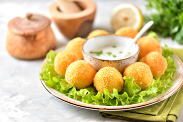 Potato croquettes and yogurt sauce with green onions. Fast food.