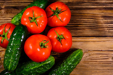 Ripe tomatoes and cucumbers on wooden table. Top view