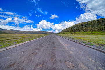 Wide angle view of the dirt road inside the Cotopaxi National Park that leads to the many volcanoes in the park, on a sunny and overcast morning.