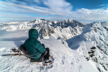 Fototapeta na wymiar Young man sitting on summit in sunny day in winter snowy High Tatra mountains in Slovakia 