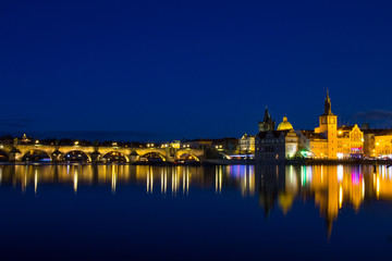 Beautiful night view of the Charles Bridge, the Old Town Bridge Tower, and the Old Water Tower, the Smetana Embankment and the Prague Beer Museum in Czech Republic New Year's Eve