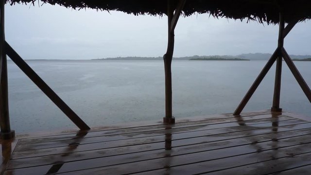 Rain on calm sea from a tropical hut over water with islands at the horizon, Caribbean sea, Panama, Central America, 50fps.