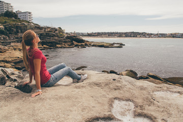 Young girl hiking around the Bondi beach in Sydney during windy weather.
