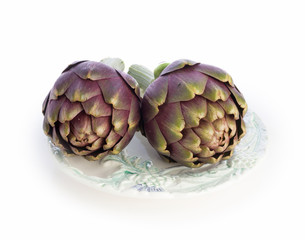 Obraz premium Two purple artichokes ready to cook on old plate
