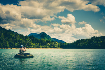 Fly fisherman on bellyboat fighting with big trout, Slovenia