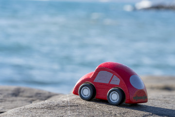 Fototapeta na wymiar Toy Car near the sea. Travel, tourism, holiday and adventure concept.