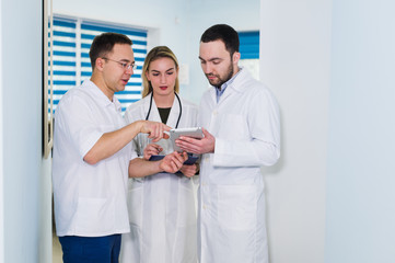 Obraz premium Portrait of happy cowerkers with clipboard while standing at hospital
