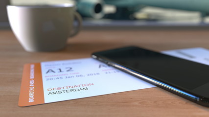 Boarding pass to Amsterdam and smartphone on the table in airport while travelling to Netherlands. 3D rendering